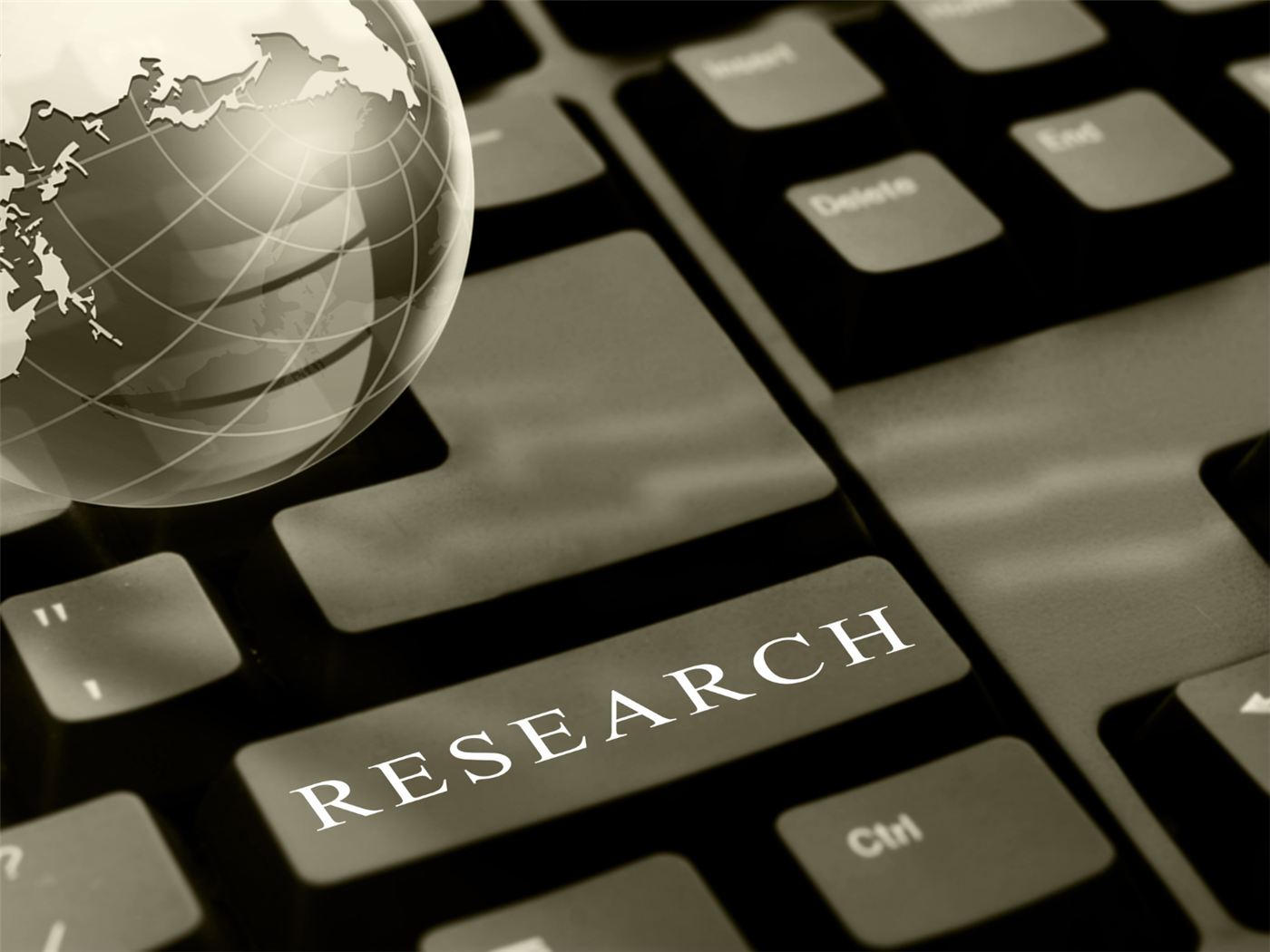 A globe resting on a keyboard beside a research key